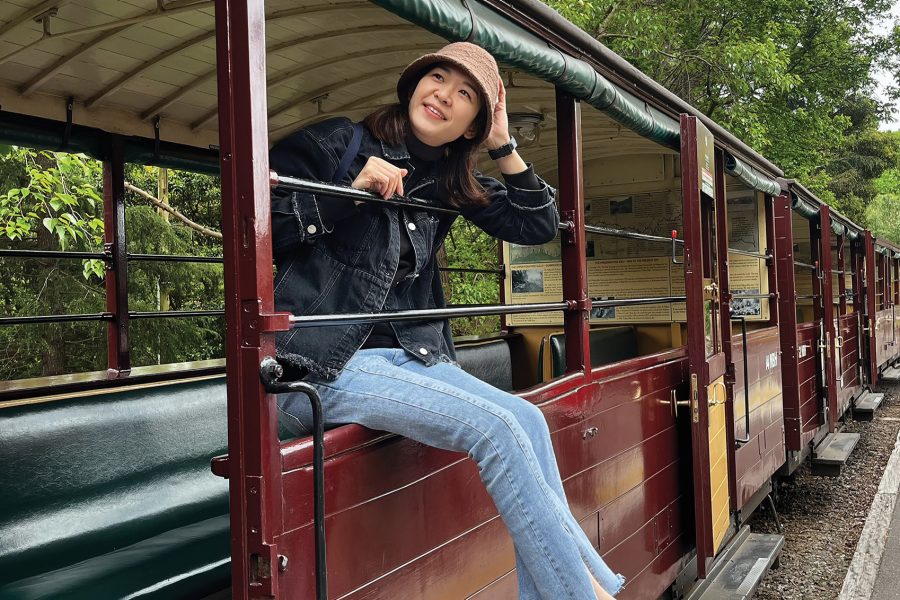 Cathay Pacific crew member Iris Koo sitting on the window frame of a Puffing Billy Railway train in Melbourne during daytime.